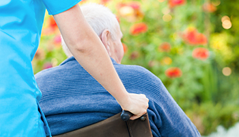Old man being carried in wheel chair